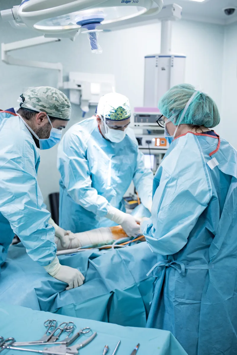 Un equipo de cirujanos en una sala de operaciones realizando una operación de ligamento cruzado anterior en un niño