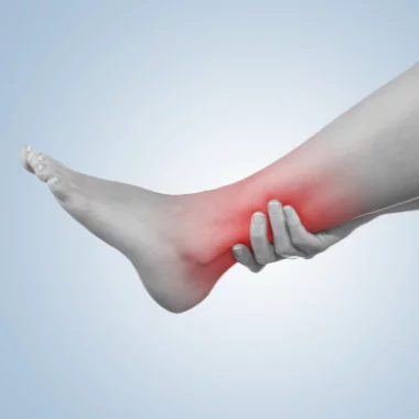 Vista lateral desde el pie y hasta mitad del gemelo donde la zona del tobillo está destacada en color rojo y una mano envuelve parte del tobillo en señal de dolor