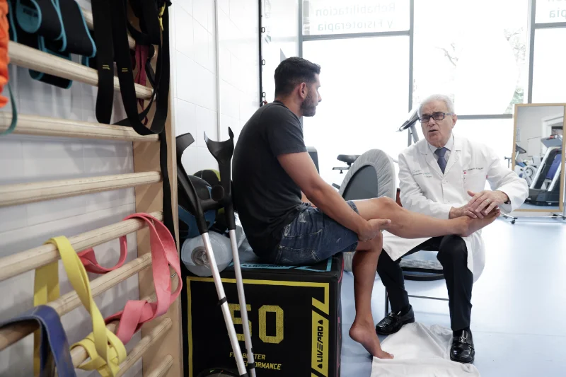 Un paciente y el Dr. Ramón Cugat sentados en el gimnasio durante una sesión de recuperación.