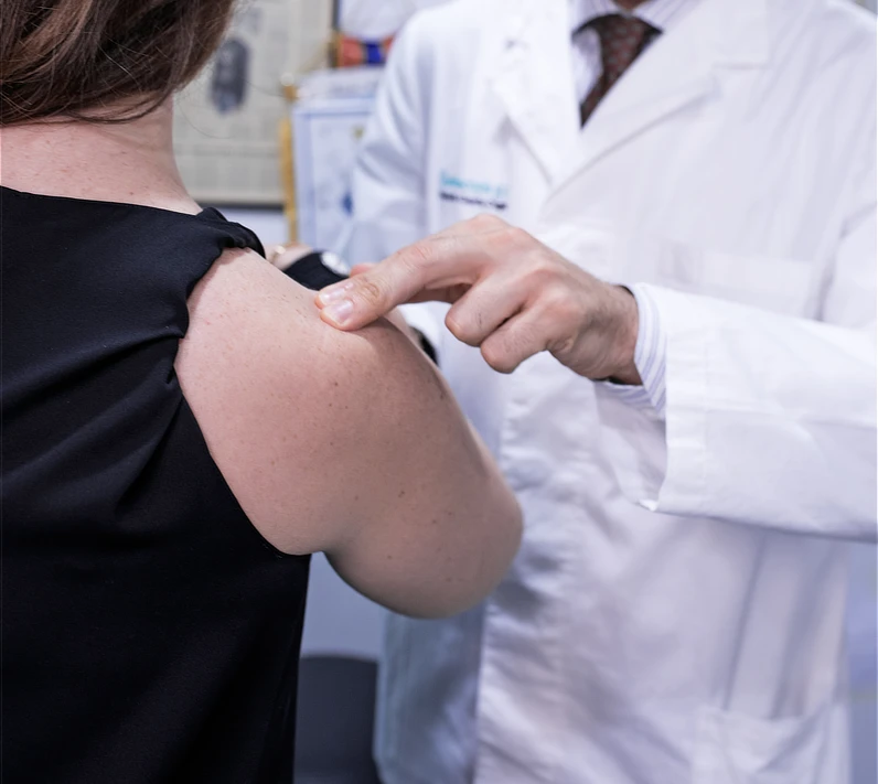 Exploración clínica del hombro por un especialista, palpando la articulación para evaluar dolor, movilidad y posible inestabilidad durante la consulta médica.