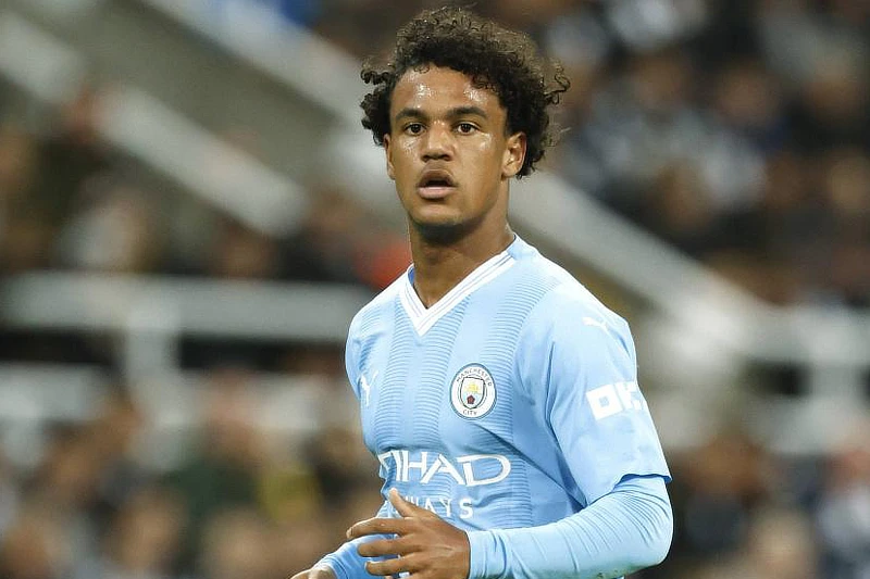 En la imagen, Oscar Bobb, joven jugador del Manchester City, aparece en pleno partido, luciendo la camiseta del equipo celeste. Se le ve atento, con expresión concentrada mientras sigue el desarrollo del juego. El estadio de fondo refleja un ambiente de competición de alto nivel, con el jugador destacado como una de las promesas del equipo. Su reciente lesión ha generado inquietud dentro del club.
