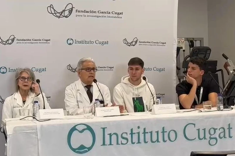 El Dr. Ramón Cugat y su equipo del Instituto Cugat participan en una rueda de prensa, acompañados de pacientes y personal médico, frente a un panel institucional.