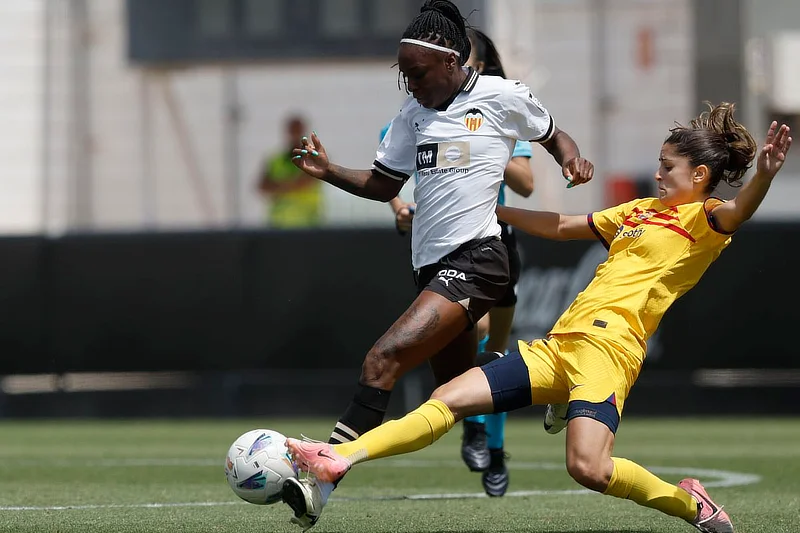 Futbolista del FC Barcelona realiza una entrada a una jugadora del Valencia durante un partido de la Liga F, con el balón en disputa en el césped. (EFE/Kai Forsterling).