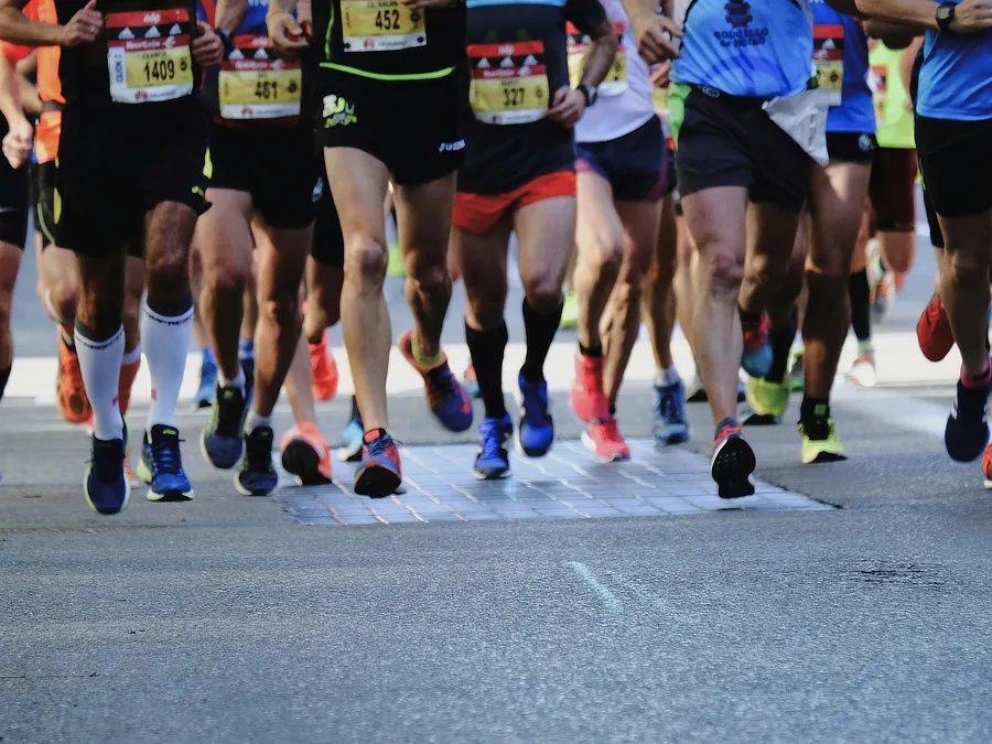 Grupo de corredores en una competición de running, con enfoque en el movimiento de las piernas y el impacto repetitivo en las rodillas.