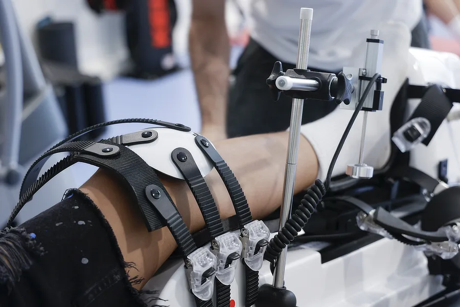 Paciente realiza ejercicios de rehabilitación con dispositivo de movilidad asistida para recuperar la función y fuerza de la rodilla tras una rotura meniscal.