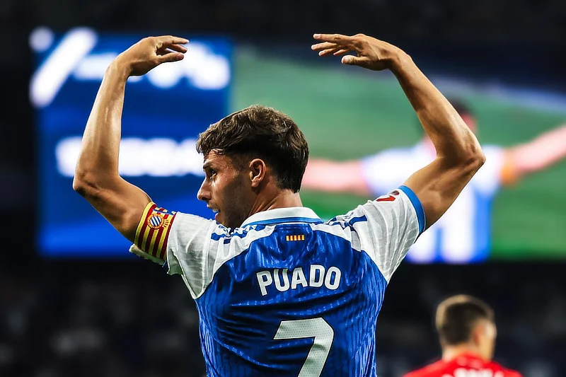 El futbolista Javi Puado, capitán del RCD Espanyol, durante un partido, levanta los brazos en el campo.