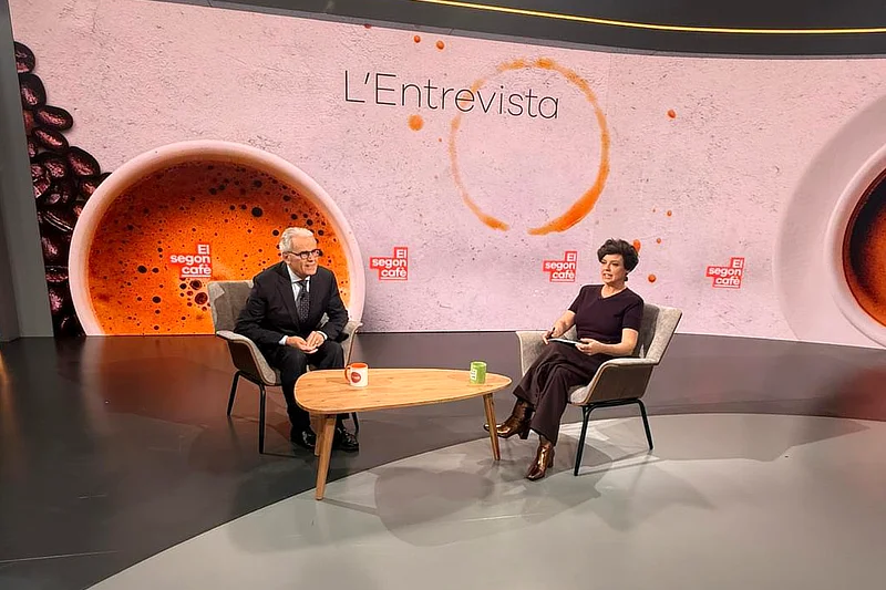 El Dr. Ramon Cugat sentado en el plató de El segon cafè de TV3 durante la entrevista con la periodista Cristina Villanueva, ambos frente a una mesa y un fondo con la imagen del programa.