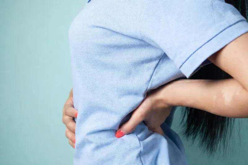 Persona con las manos en la zona lumbar en actitud de dolor, ilustrando cuándo el hecho de que crujen las articulaciones requiere una valoración médica según explica El Nacional.