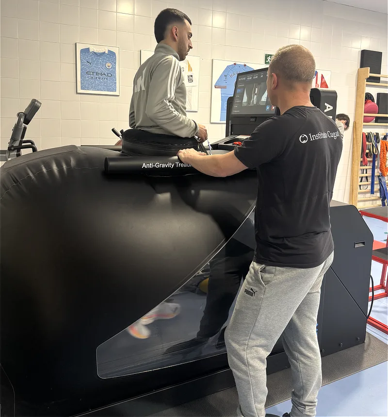 Paciente deportista corriendo a alta velocidad dentro de la cinta Alter G. La imagen muestra el sistema de suspensión por aire que permite el entrenamiento de carrera (return to run) eliminando gran parte del peso corporal.