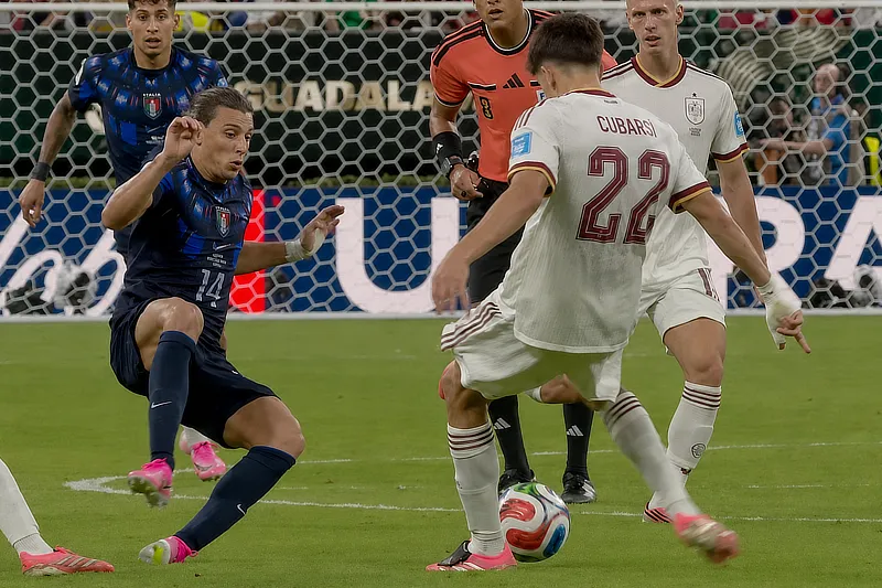 El futbolista Pau Cubarsí con el dorsal 22 de la selección española chuta el balón ante la entrada de un jugador rival de Uruguay durante un partido.