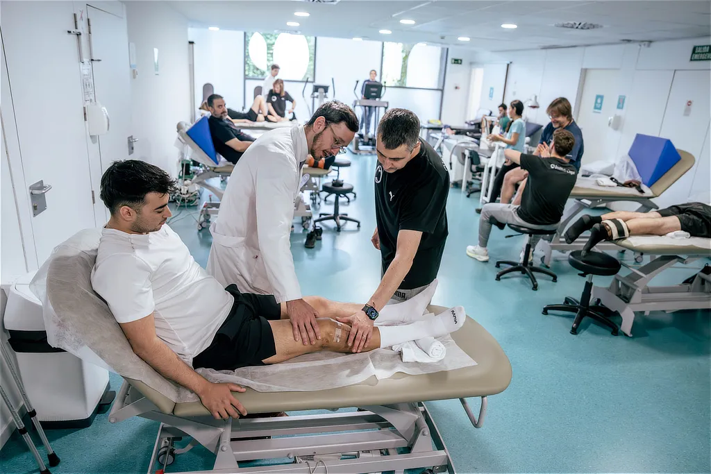 Two specialists examine a patient's knee on a treatment table in the physiotherapy department at Instituto Cugat in Barcelona.