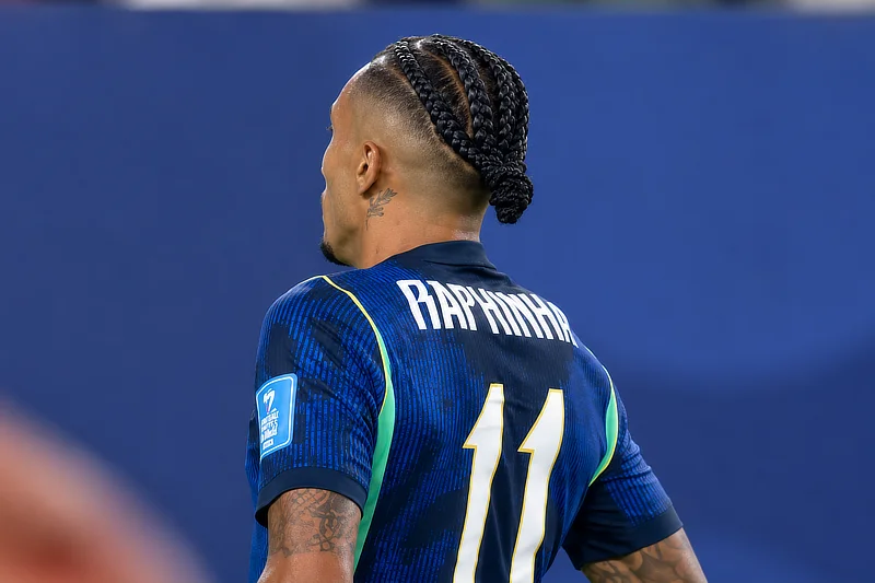 Vista de espaldas del futbolista brasileño Raphinha, vistiendo la camiseta azul con el número 11 de la selección de Brasil, durante un partido de fútbol.