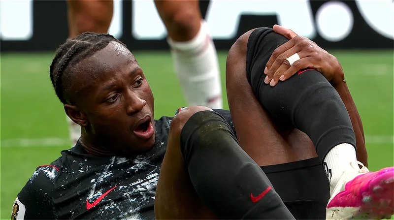 El jugador canadiense Ismaïl Koné tumbado sobre el césped con gesto de dolor mientras se sujeta la pierna izquierda tras sufrir una lesión en el terreno de juego.