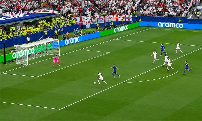 Jugada de partido de fútbol en campo abierto entre las selecciones de Inglaterra y Croacia en un gran estadio con publicidad de Aramco de fondo.