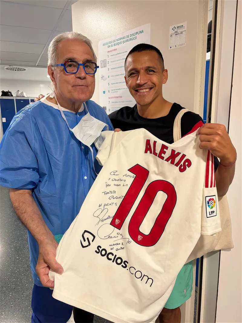 El Dr. Ramón Cugat y Alexis Sánchez sostienen una camiseta firmada del Sevilla FC con el número 10.