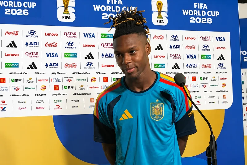 El futbolista Nico Williams con la camiseta técnica de la selección española durante una rueda de prensa en el Mundial 2026 frente a un panel oficial de logotipos de la FIFA.