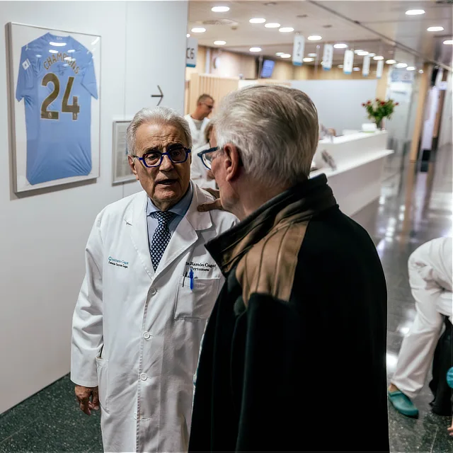 Unidad de tumores óseos 5 Qué nos diferencia Dr. Ramón Cugat conversando con un paciente en el pasillo del Instituto Cugat, junto a la zona de recepción y consultas.