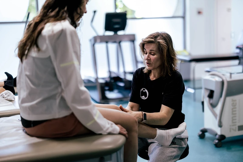 Profesional sanitaria valorando la rodilla de una paciente durante una consulta en Instituto Cugat en Barcelona.